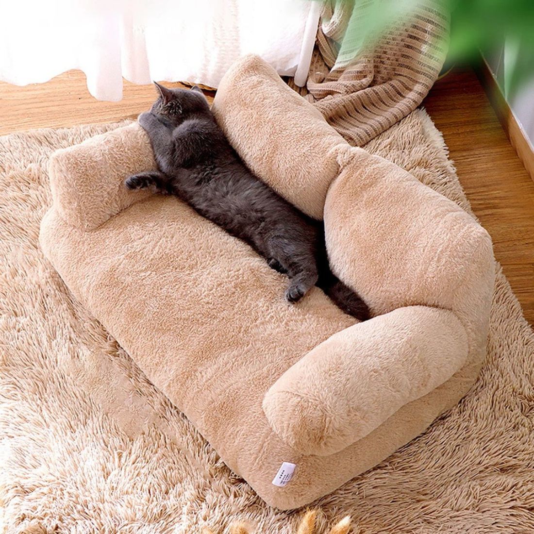 Chat gris étendu de tout son long sur un coussin en forme de canapé beige