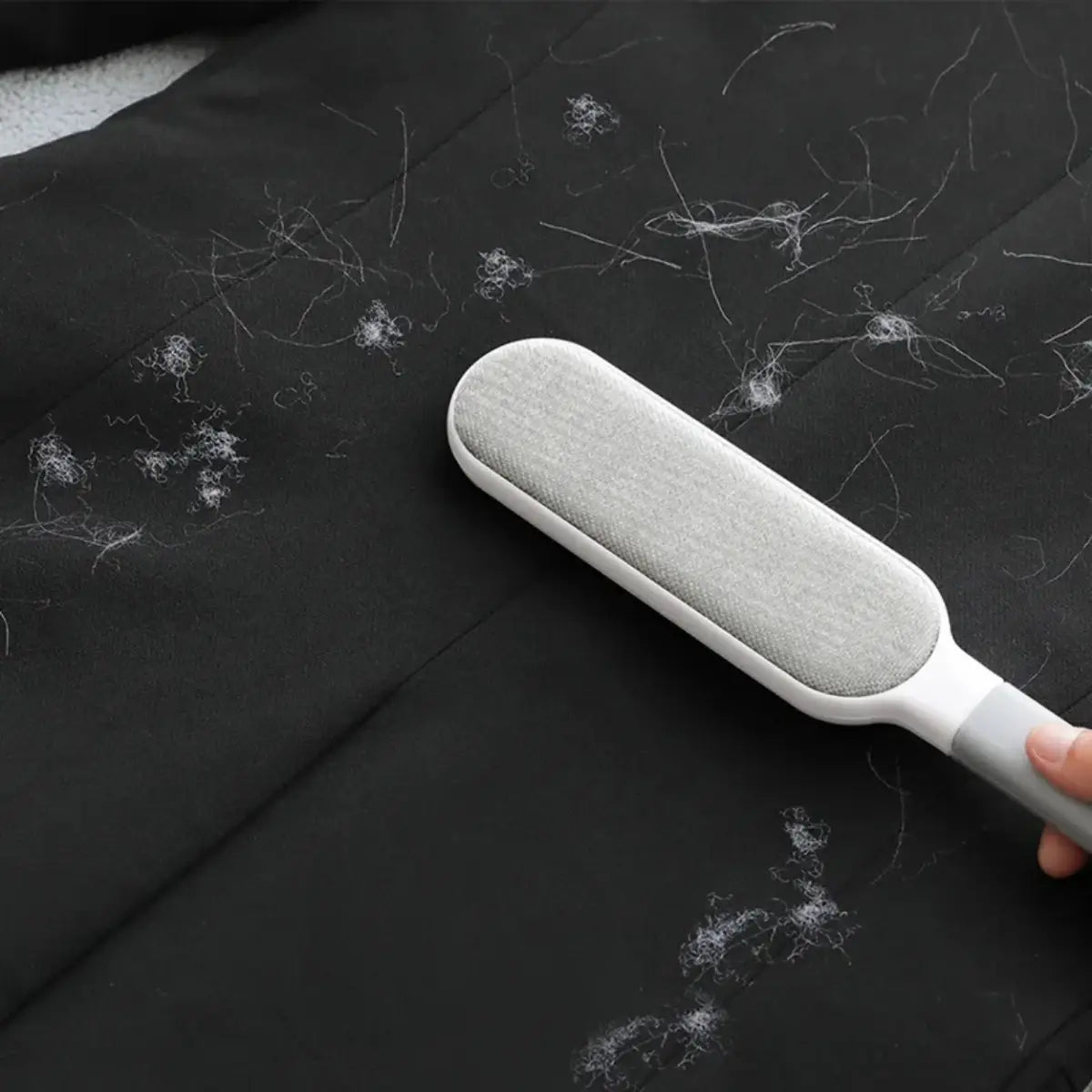 Brosse anti-peluches en action sur un tissu noir pour un nettoyage efficace.