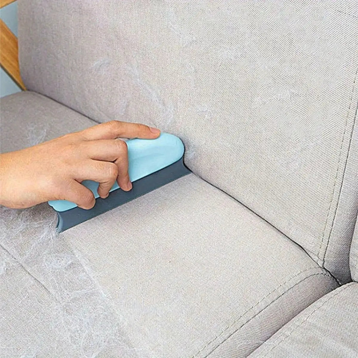 brosse poil chat utilisée pour retirer les poils d'animaux sur un canapé clair - vue de dessus