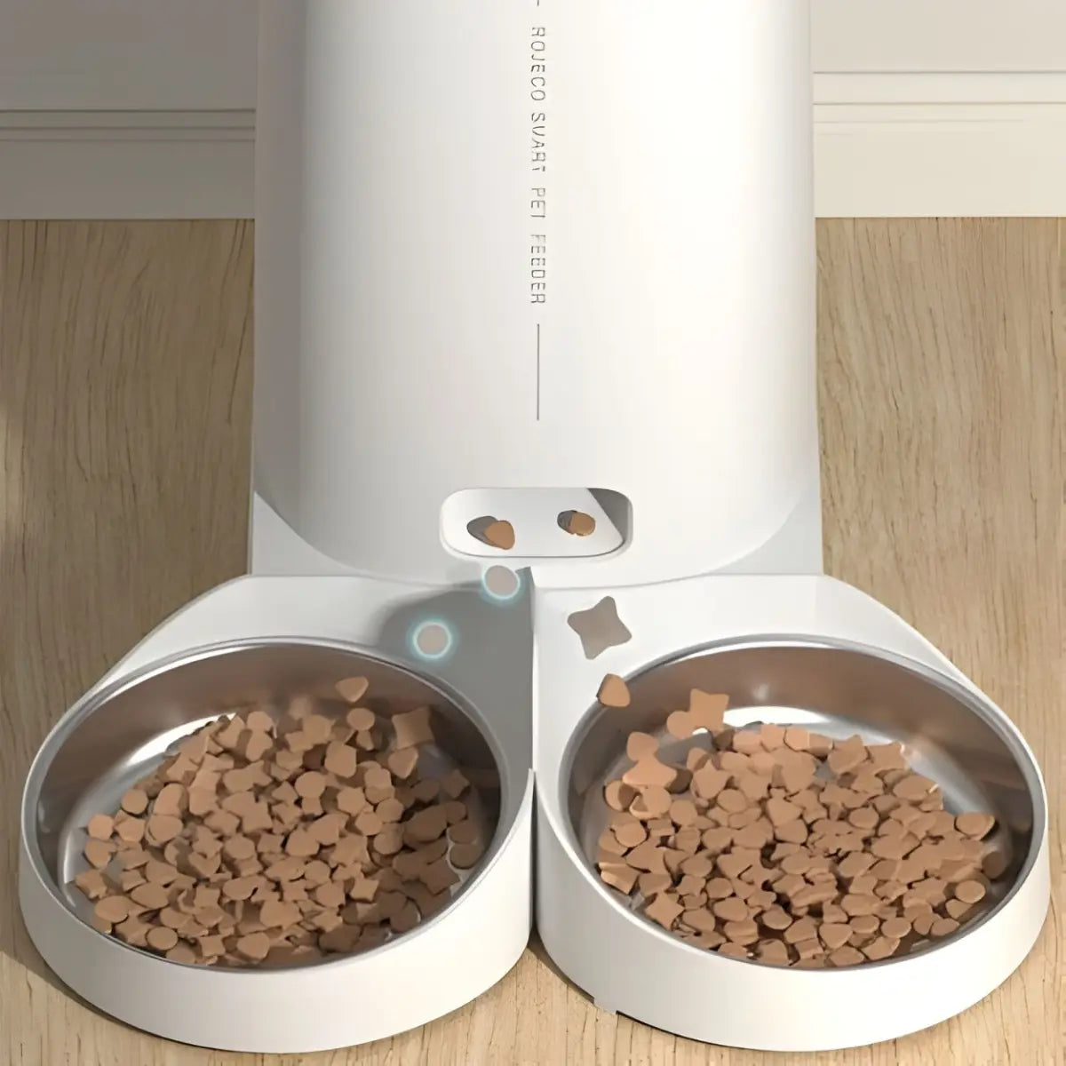 Distributeur de croquettes pour chat avec deux bols en acier inoxydable sur un sol en bois.