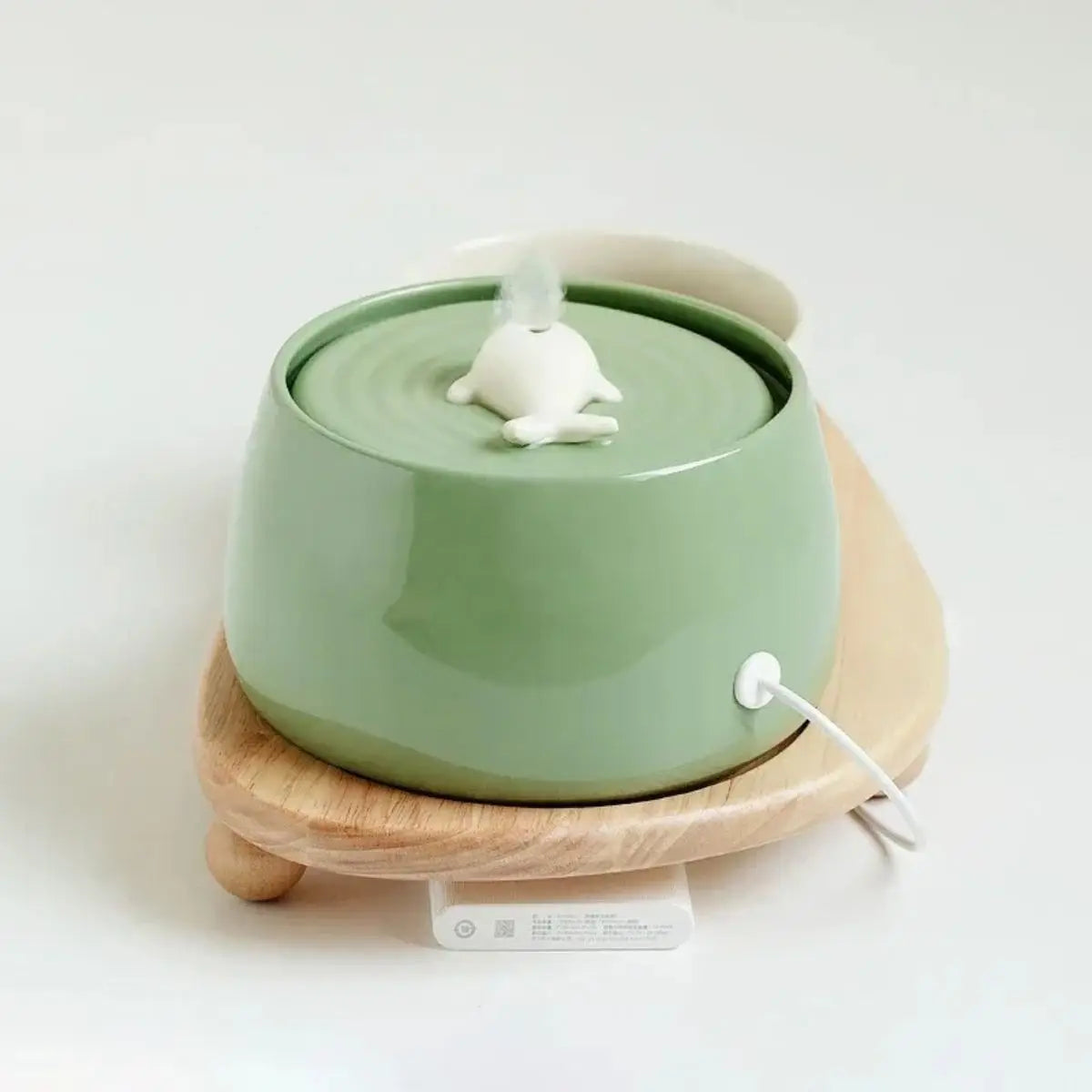 Fontaine à eau chat VOFORD céramique verte, débit continu, câble USB, posée sur support en bois.