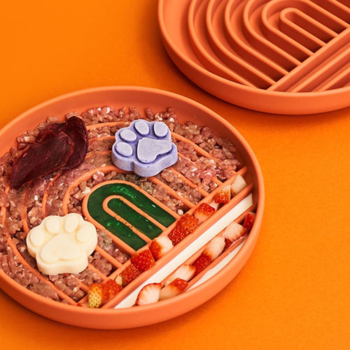 gamelle anti glouton chat remplie de viande hachée et de fraises sur fond orange