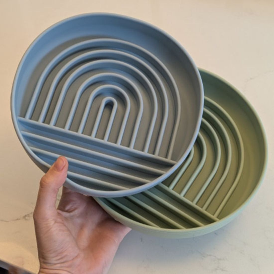 Gamelles pour chat avec motif en labyrinthe tenues à la main sur fond clair