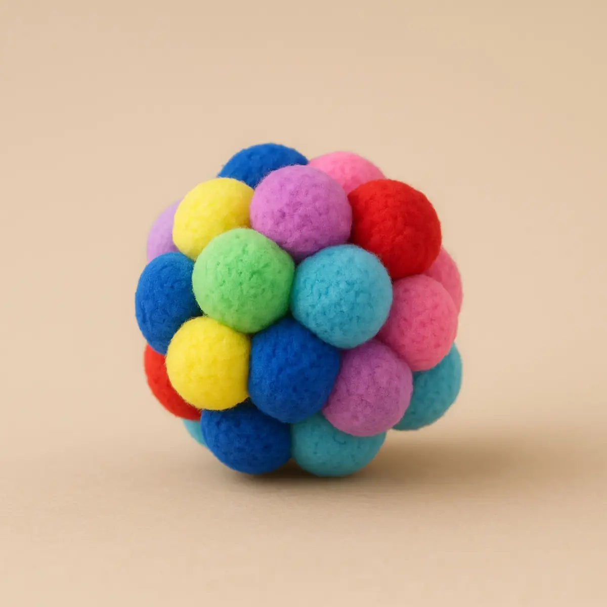 Jouet pour chat coloré en forme de balle composée de pompons arc-en-ciel.