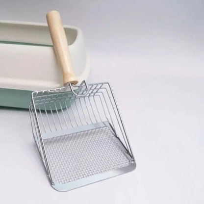pelle a litiere pour chat en inox avec manche en bois devant un bac à litière